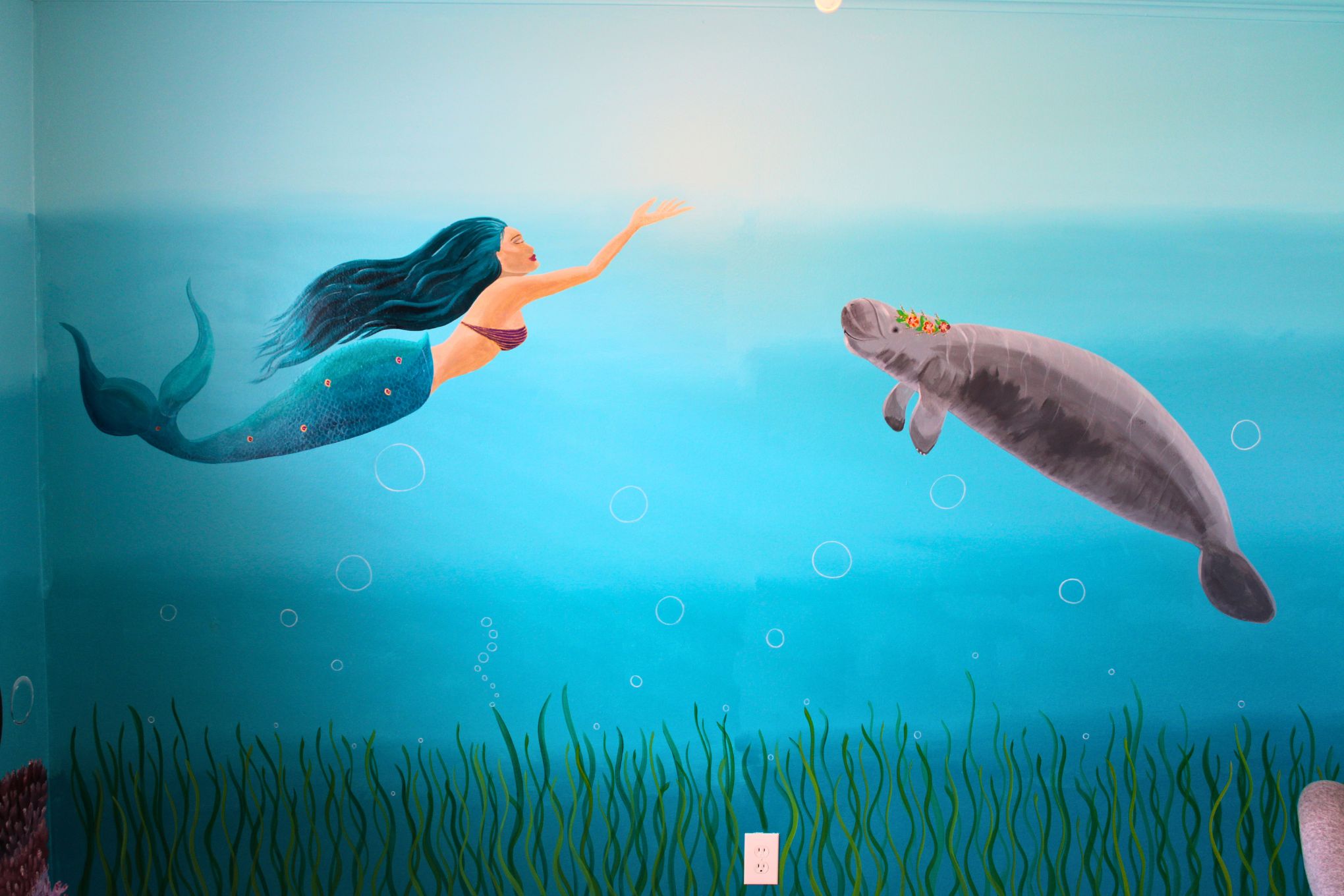Mermaid and manatee above seagrass bed